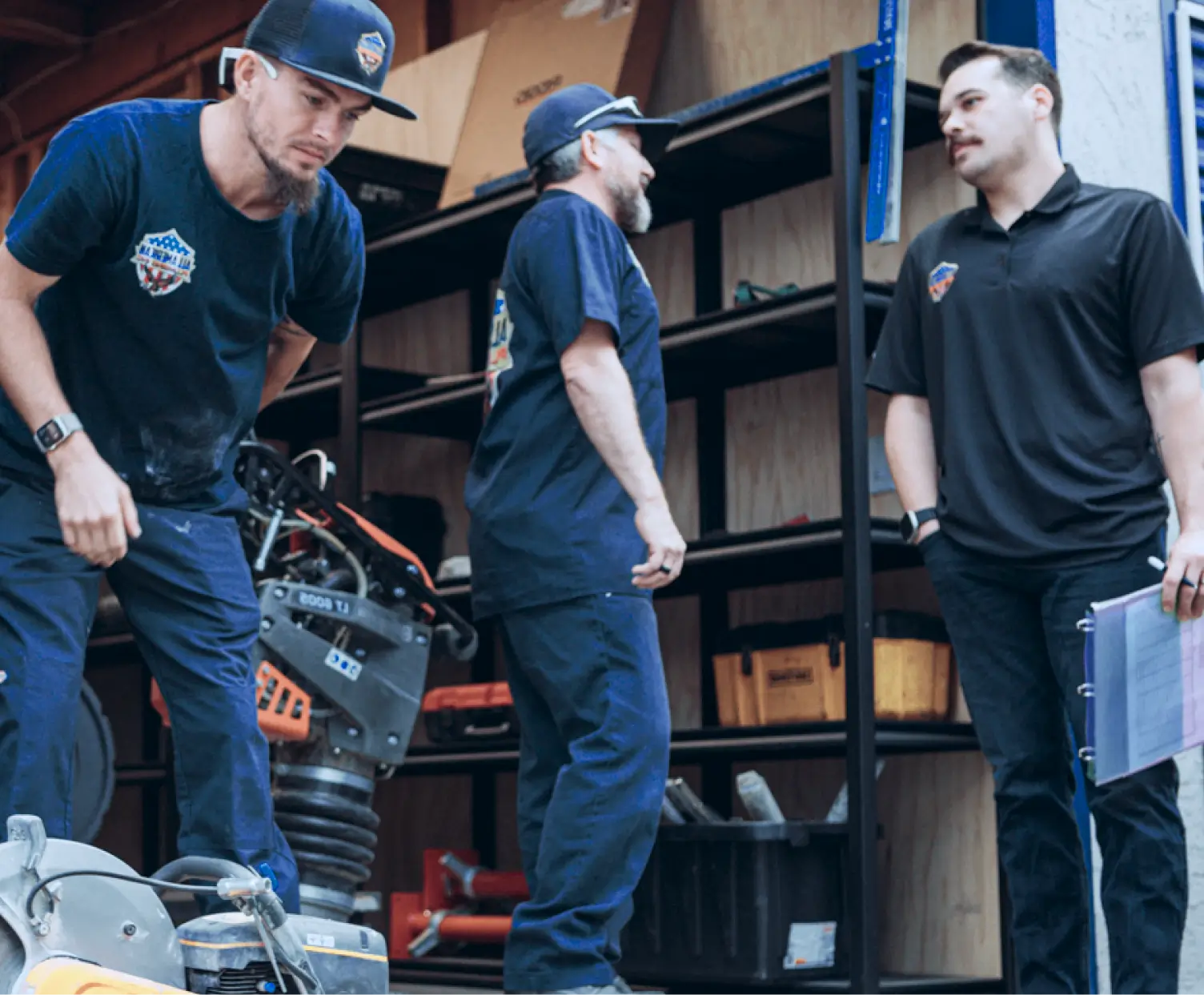 Home Services Business Management Software - Housecall Pro - Housecall Pro All American Plumbing team members in workshop setting with tools and equipment, representing loyal customers of using Housecall Pro’s software for 7 years.